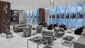 A modern living room with a city view, contemporary furniture, and a large window overlooking the skyline. - Envue, Autograph Collection (Weehawken)