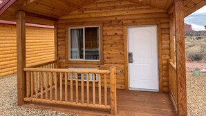 Une cabane en bois avec une véranda, une fenêtre et une porte.