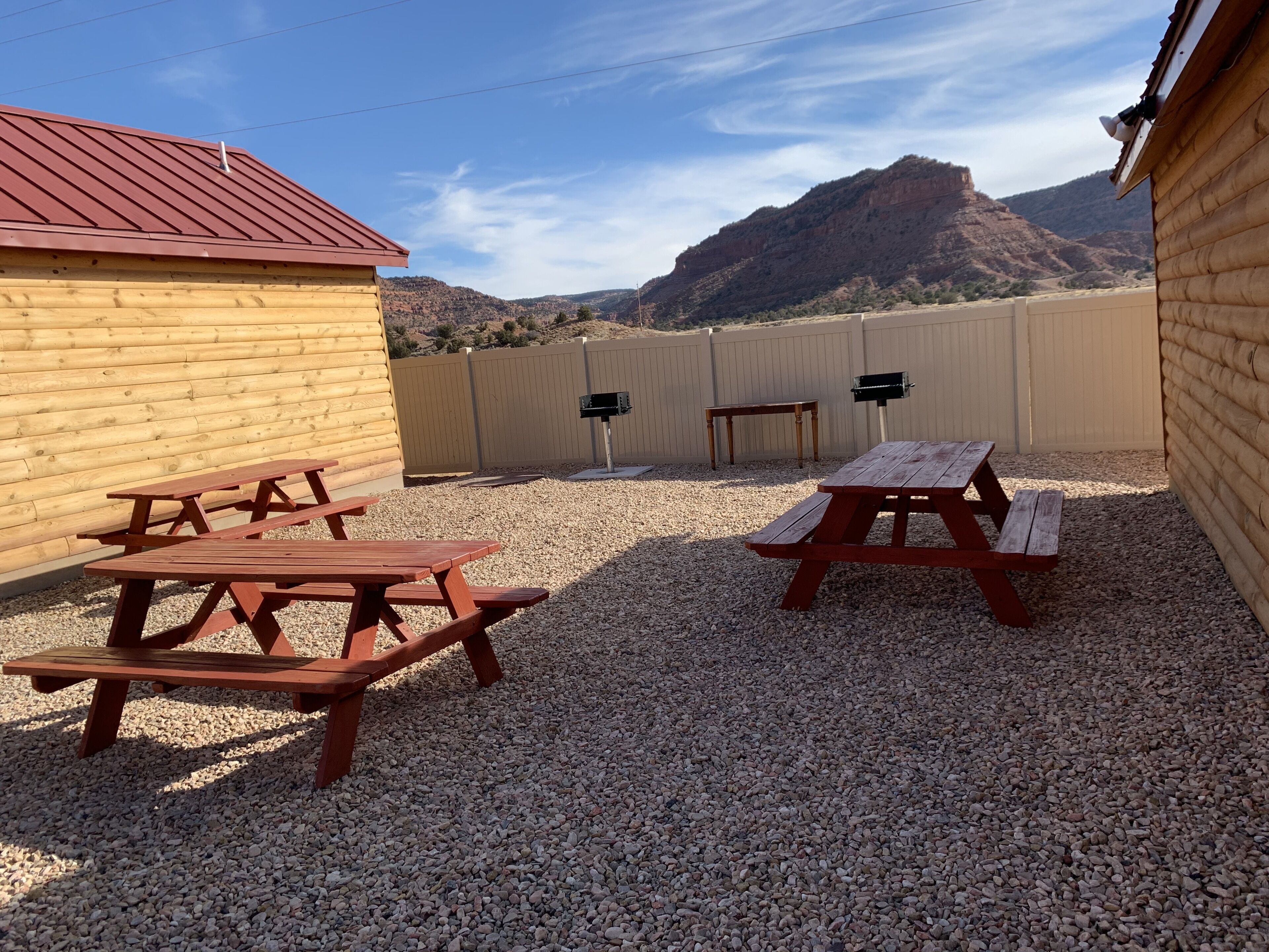 A patio area with picnic tables and a view of a mountain range.