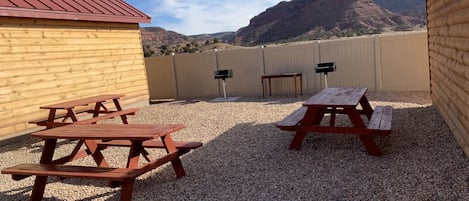A patio area with picnic tables and a view of a mountain range.
