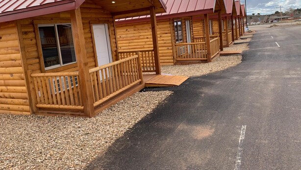 Une rangée de chalets en rondins, avec des toits en métal, des balcons en bois et des allées recouvertes de gravier.