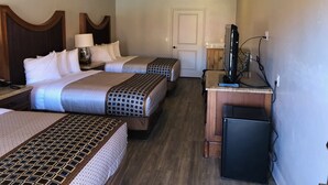 Une chambre d’hôtel avec deux lits, un bureau avec une télévision et un ventilateur de plafond.