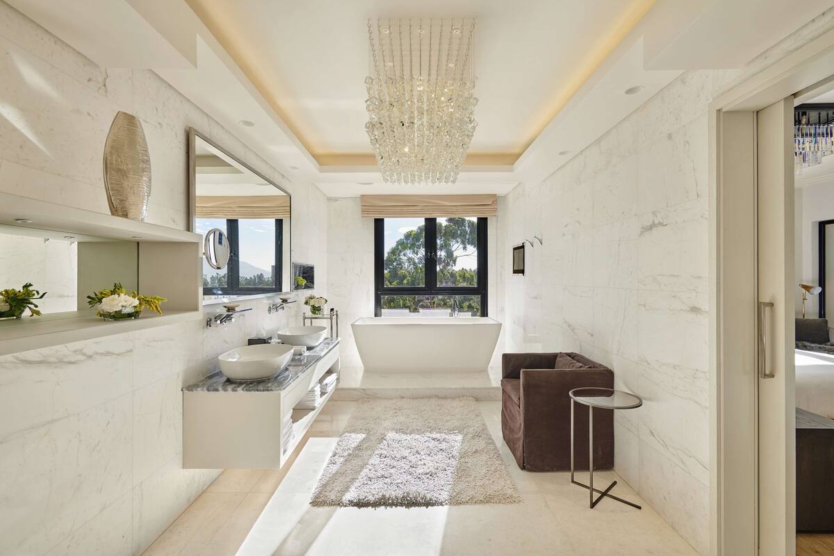 A modern bathroom with a large mirror, a bathtub, and a vanity with a sink.