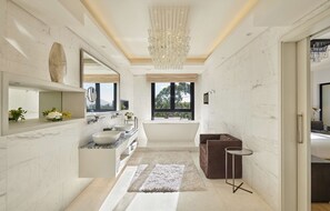 A modern bathroom with a large mirror, a bathtub, and a vanity with a sink.