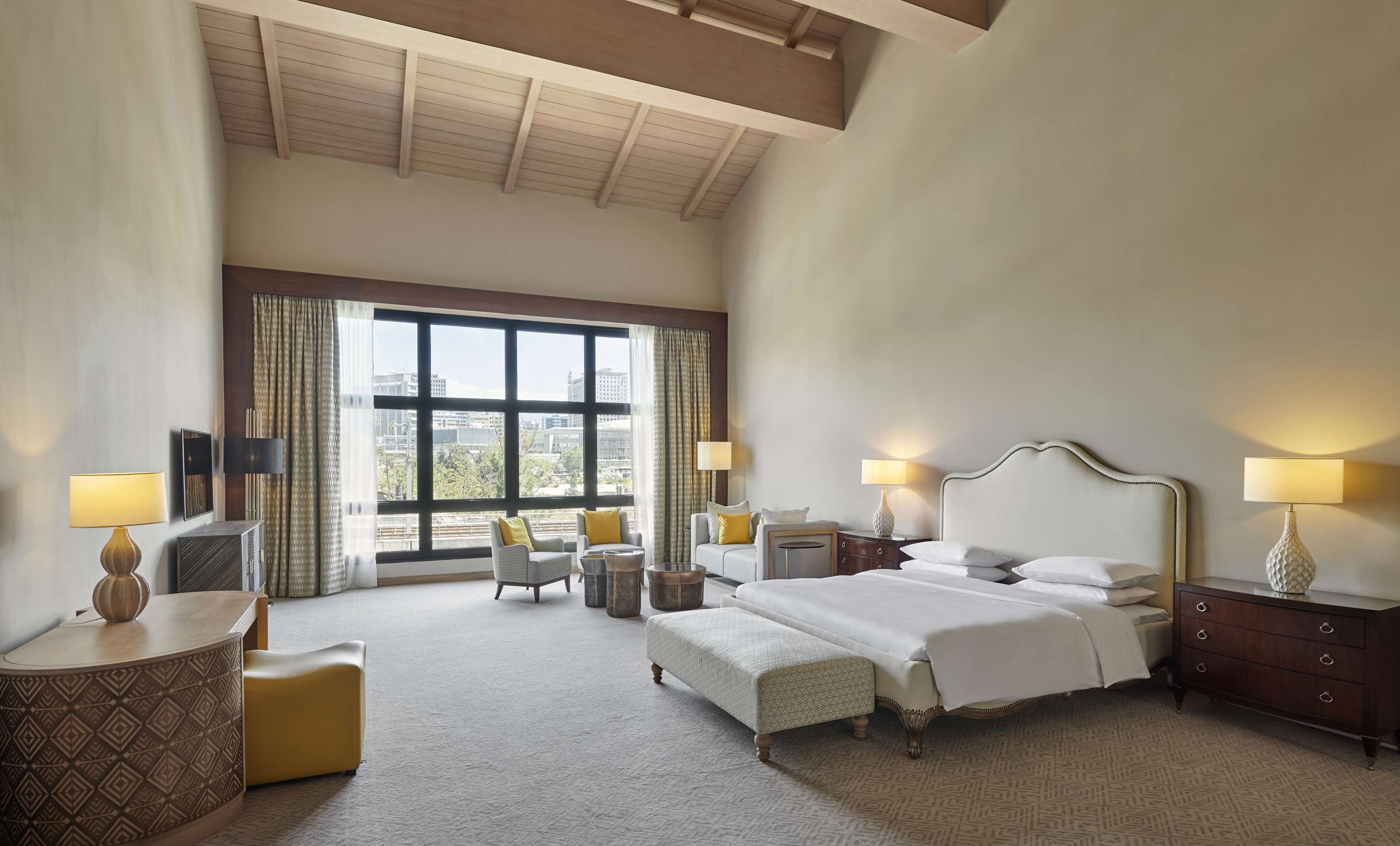 Amplia habitación de hotel con una cama grande, dos sillones, una mesita y un escritorio.
