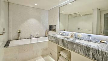 A modern bathroom with a large bathtub, two sinks, and a large mirror.