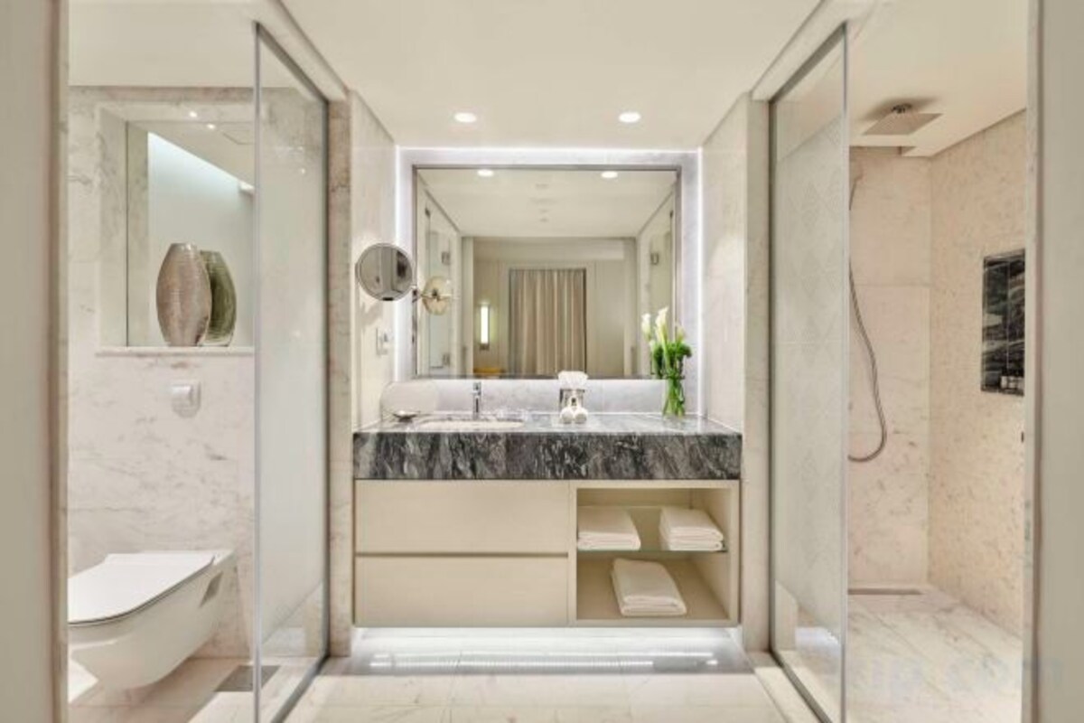 A modern bathroom with a marble sink, a large mirror, and a walk-in shower.