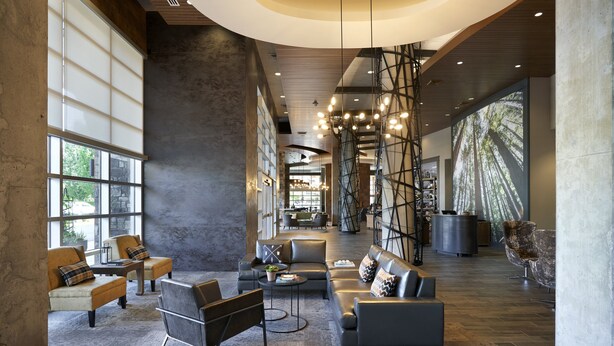 Un hall d’entrée spacieux, doté de meubles modernes, de grandes fenêtres et d’un plafond haut avec des poutres apparentes.