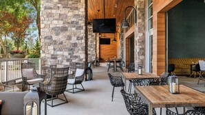 Une terrasse extérieure avec des murs en pierre, un plafond en bois et plusieurs espaces aménagés avec des tables et des chaises.