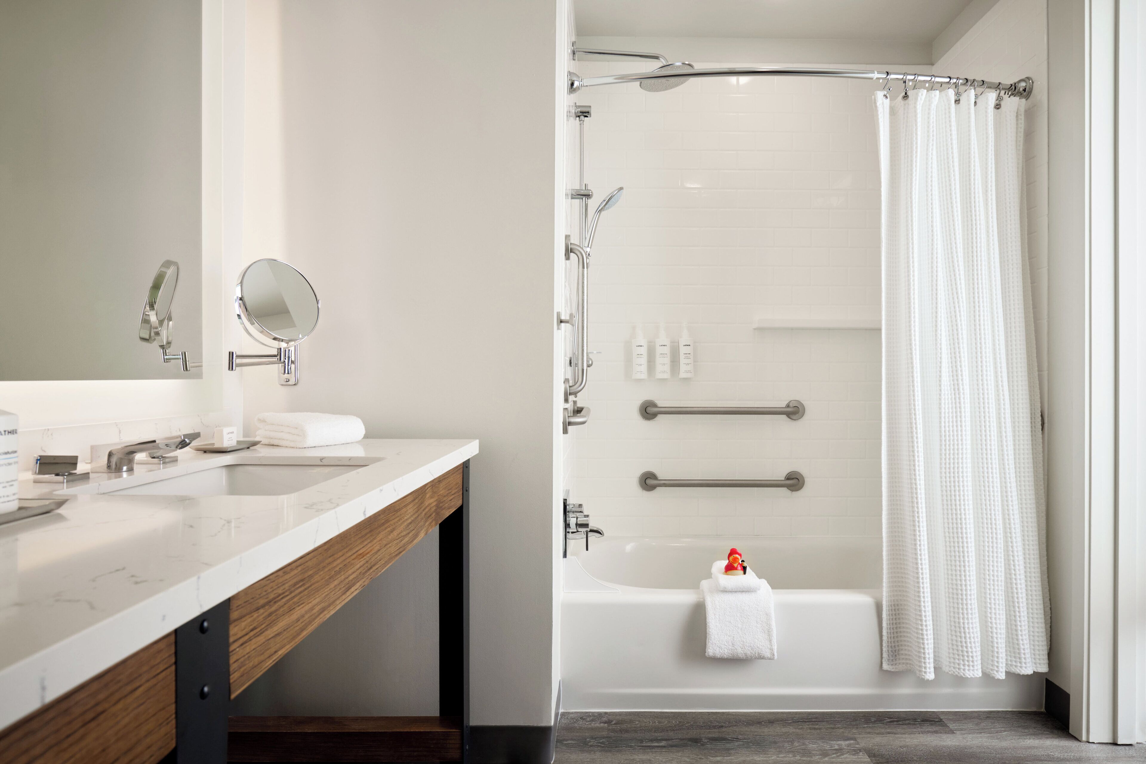 A modern bathroom with a marble vanity, a shower with a glass door, and a bathtub with a towel.