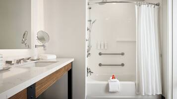 A modern bathroom with a marble vanity, a shower with a glass door, and a bathtub with a towel.