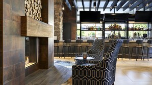 Un espace bar moderne doté d’une cheminée, de sièges et offrant une vue sur l’extérieur.