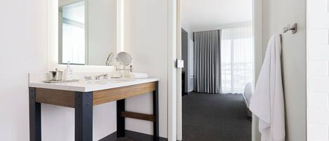 A modern bathroom with a wooden vanity, a mirror, and a towel rack.
