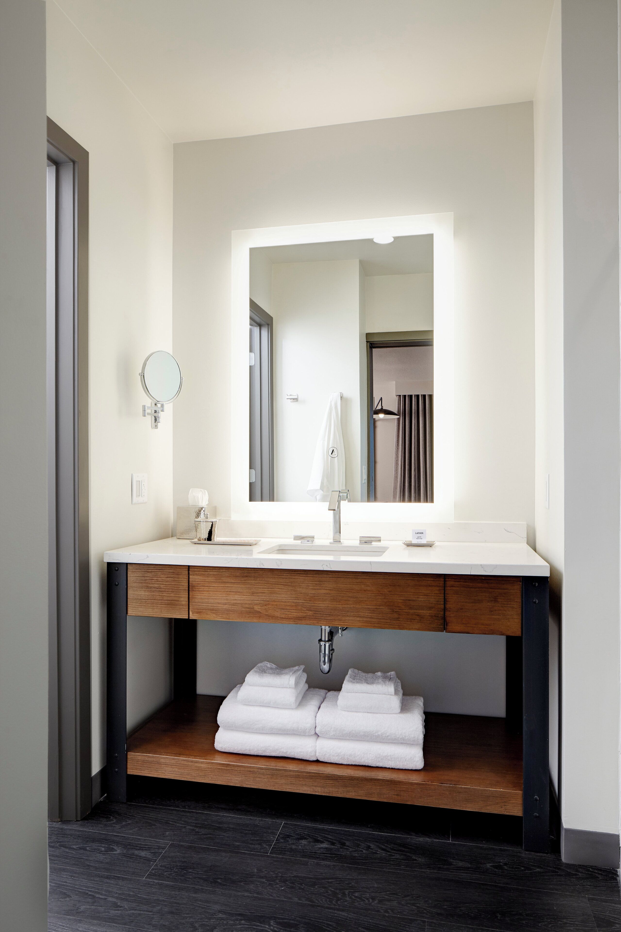 Un baño moderno con un tocador blanco, un espejo grande y un perchero para toallas.