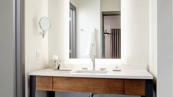 Un baño moderno con un tocador blanco, un espejo grande y un perchero para toallas.