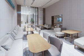 A modern lounge area with sofas, tables, and chairs arranged for socializing. - Ji Hotel (Huai'an)