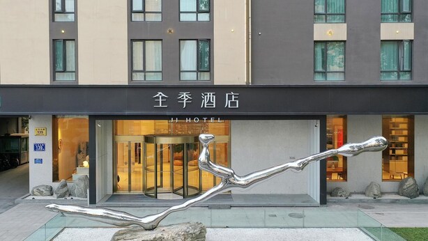 Een hotelingang met een modern beeldhouwwerk ervoor.