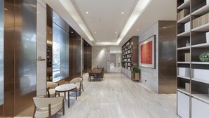 Een modern interieur met een lange gang, een eethoek met tafel en stoelen, en inbouwboekenplanken.