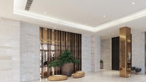 Een moderne lobby met marmeren vloer, een grote potplant en een receptiebalie.