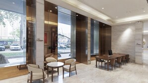 A modern hotel lobby with a marble floor, a wooden reception desk, and a seating area with chairs and tables. - Ji Hotel (Huai'an)