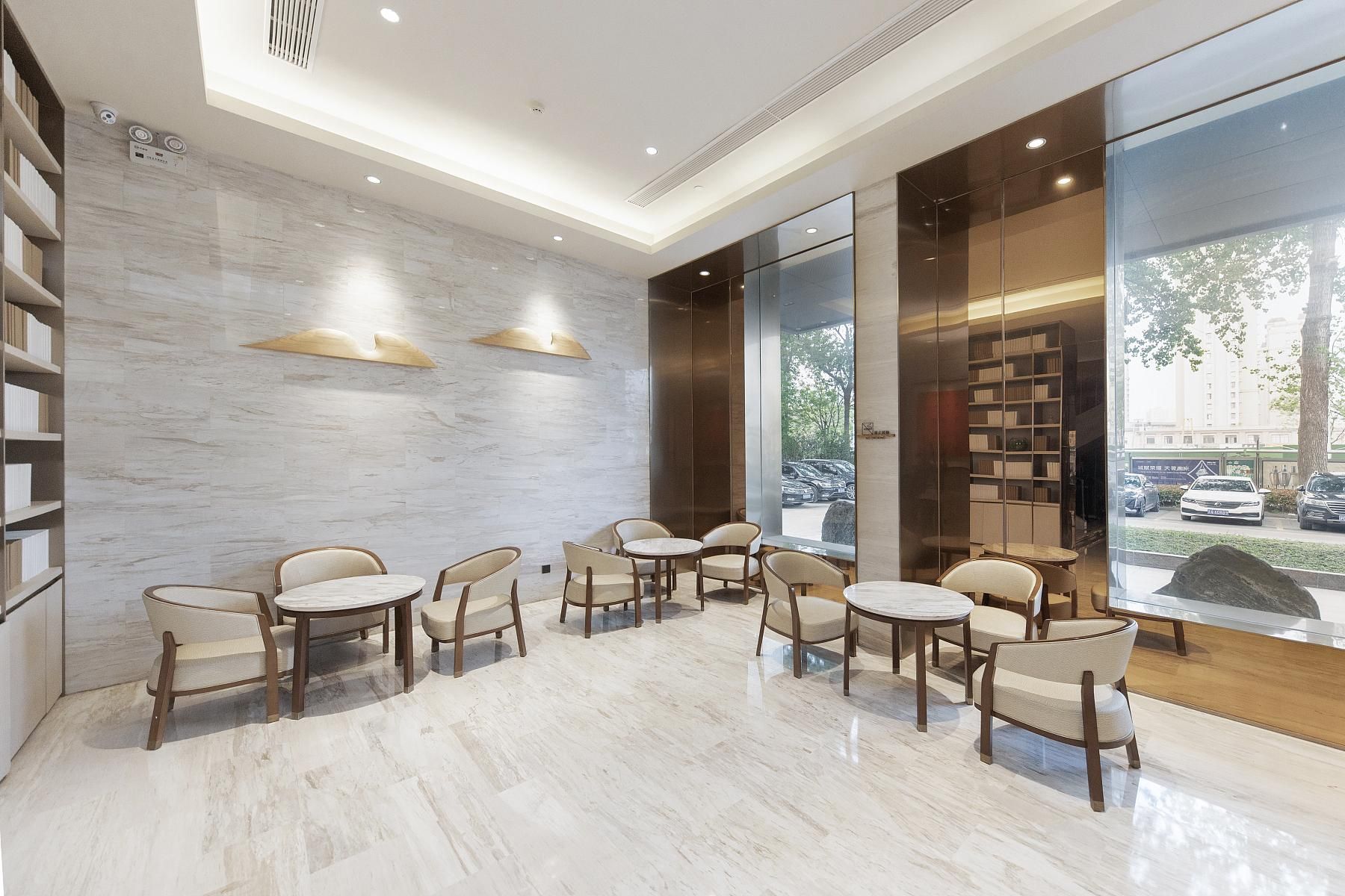 Un vestíbulo moderno con suelo de mármol, sillas de madera y estanterías.