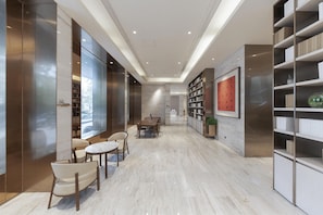 A modern interior with a long hallway, a dining area with a table and chairs, and built-in bookshelves. - Ji Hotel (Huai'an)