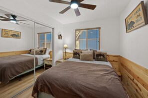 Ein Hotelzimmer mit zwei Betten, einem Deckenventilator, einem Fenster mit Jalousien und einem Wandzeichen.
