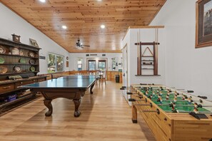Ein geräumiger Raum mit Tischtennisplatte, Kicker und Billardtisch.
