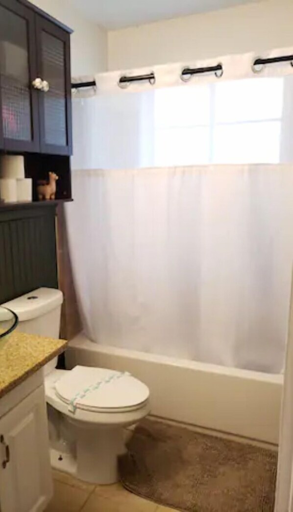 Une salle de bain avec des toilettes, un rideau de douche et un meuble au-dessus des toilettes.