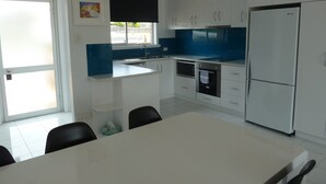 A modern kitchen with white cabinets, a black countertop, a built-in oven, and a refrigerator.