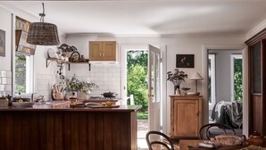 A kitchen with a wooden island, white tiled backsplash, and a hanging light fixture. There is a door leading to a garden. - The Church at Lyonville ~ Daylesford Region (Lyonville)