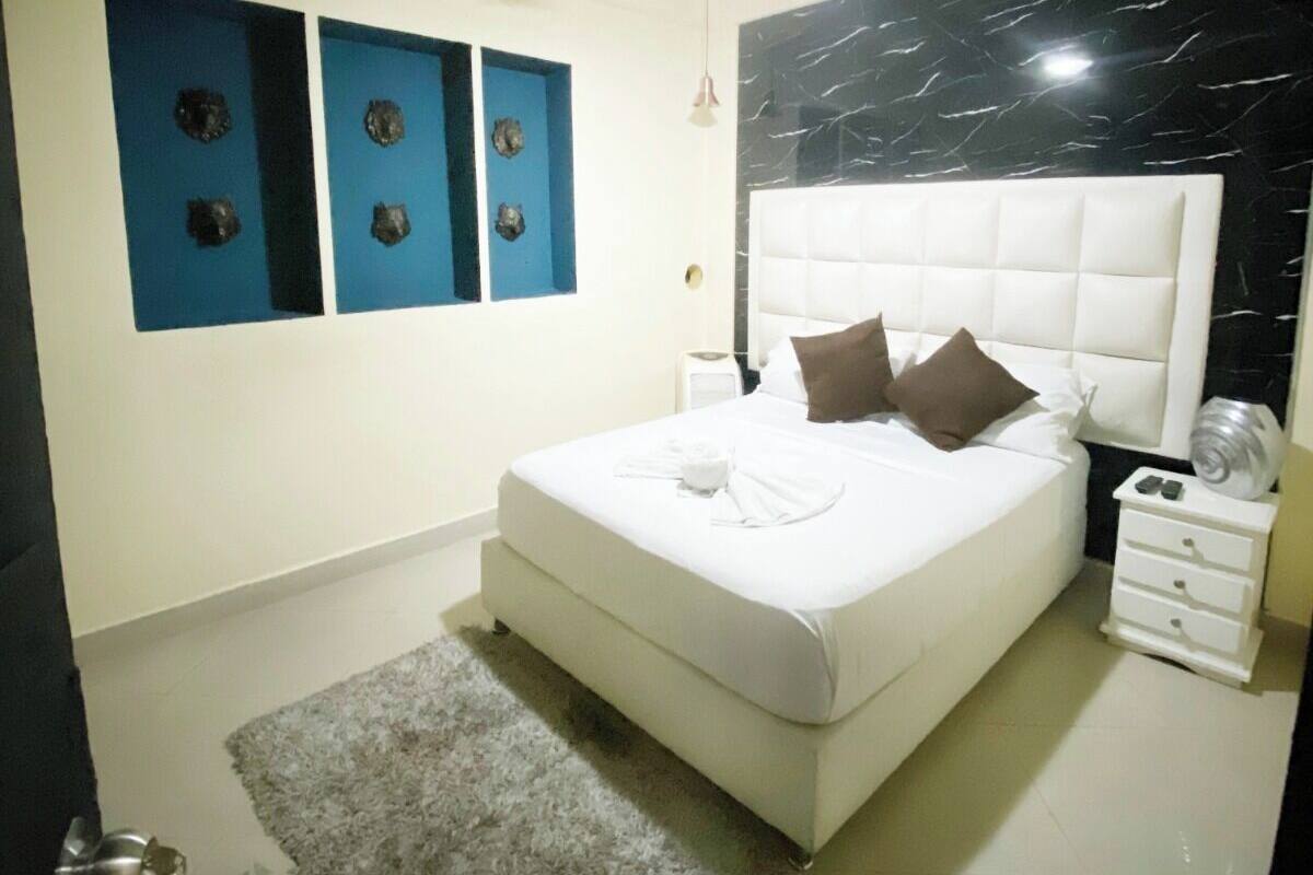 A bedroom with a bed, a ceiling fan, a nightstand, and wall decorations.