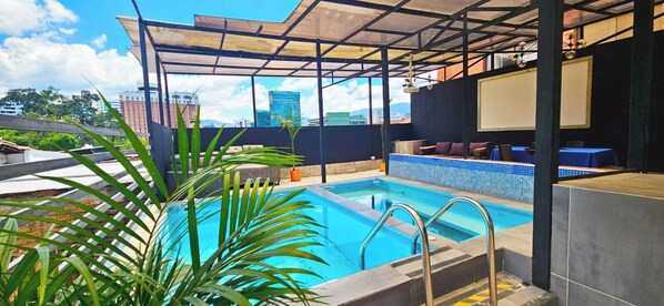A rooftop pool with a view of city buildings, a covered seating area, and potted plants. - $ PROMO $ 3 Bedrooms with Bathrooms apartment & Jacuzzi in Lleras park @Poblado (Medellín)