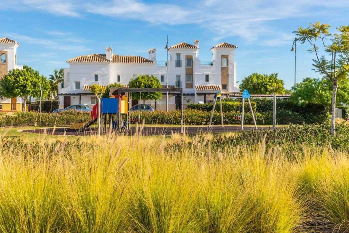 Un immeuble résidentiel à la façade symétrique, doté de nombreux balcons et agrémenté d’un jardin bien entretenu.