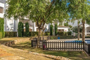 A courtyard with a pool, surrounded by trees and a stone wall.