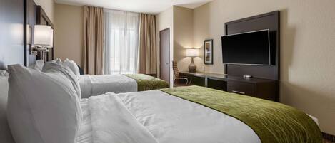 Een hotelkamer met twee bedden, een televisie, een bureau en een raam met gordijnen.