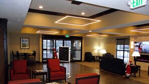 Un hall de hotel con mostrador de recepción, zona de estar y una pantalla de televisión.