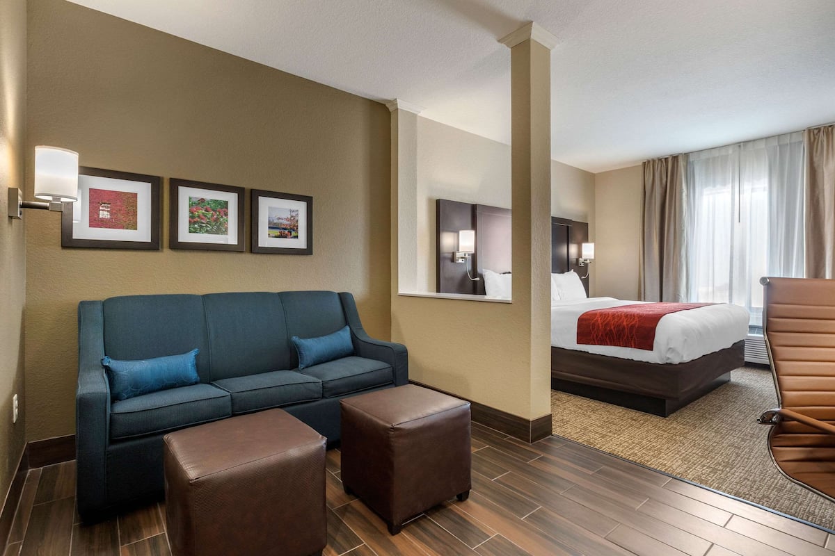 Una habitación de hotel con sofá, reposapiés, cama y una silla.