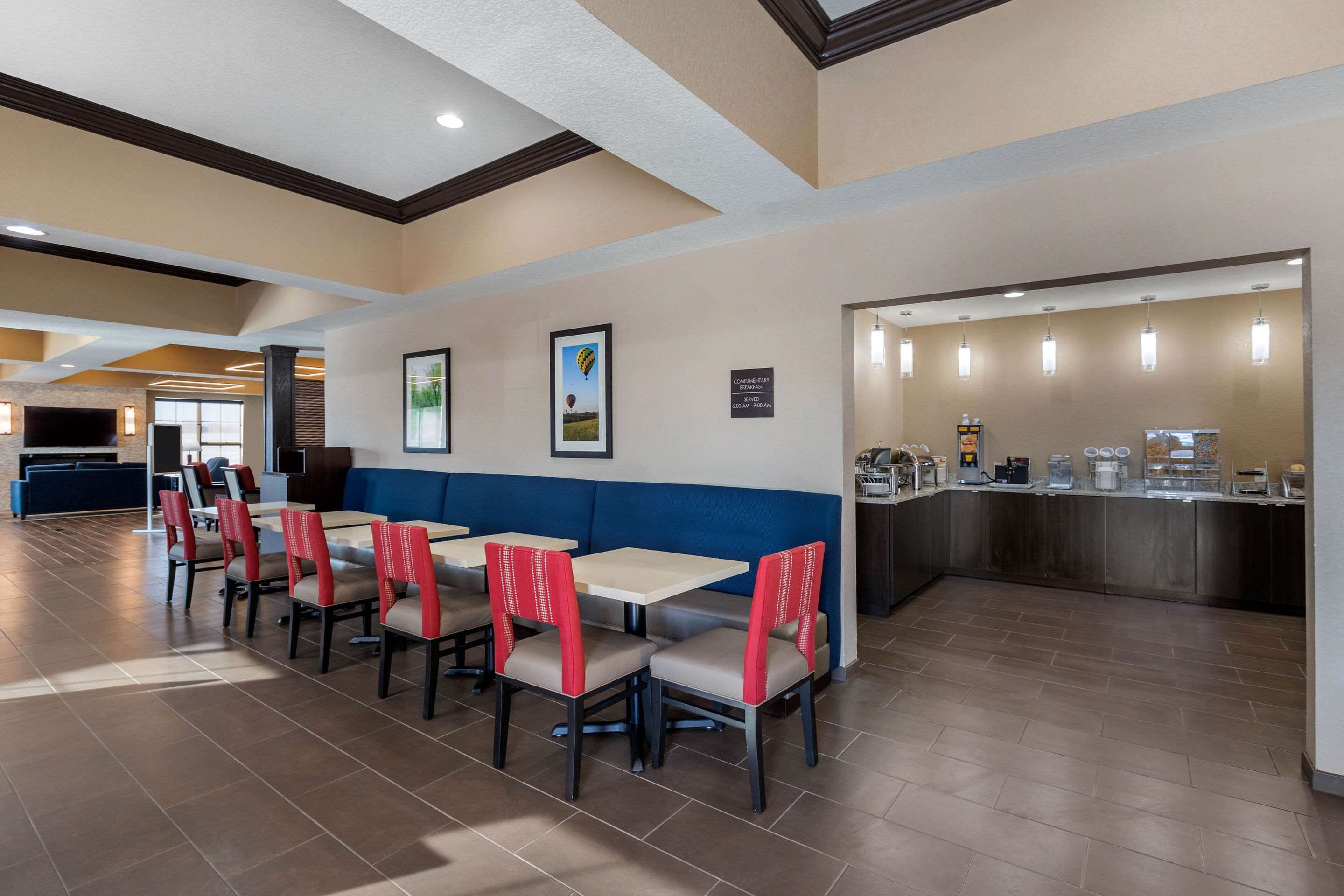 A hotel dining area with booths and tables, a counter with a coffee station, and a fireplace.