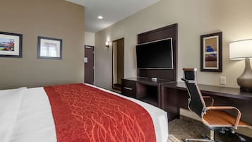 Una camera d'albergo con un letto, una scrivania, una sedia, una televisione e quadri appesi al muro.