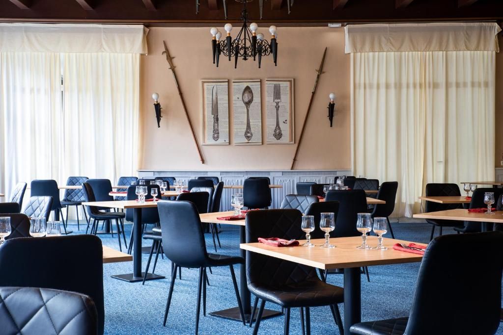 Restaurante com mesas, cadeiras, lustre e obras de arte nas paredes.