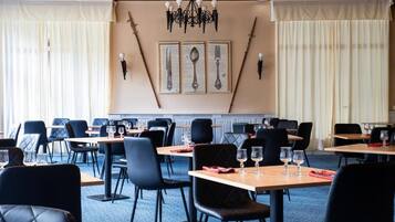 Restaurante com mesas, cadeiras, lustre e obras de arte nas paredes.