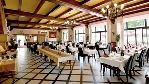 A large dining hall with high ceilings, chandeliers, and a checkered floor pattern. Tables are set with white tablecloths and chairs. - Logis Hotel du Chateau (Josselin)