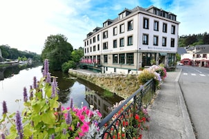 Um hotel com vista para o rio, área de estar coberta ao ar livre e um jardim com flores.