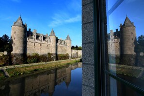 A castle with multiple towers and a moat, viewed through a window. - Logis Hotel du Chateau (Josselin)