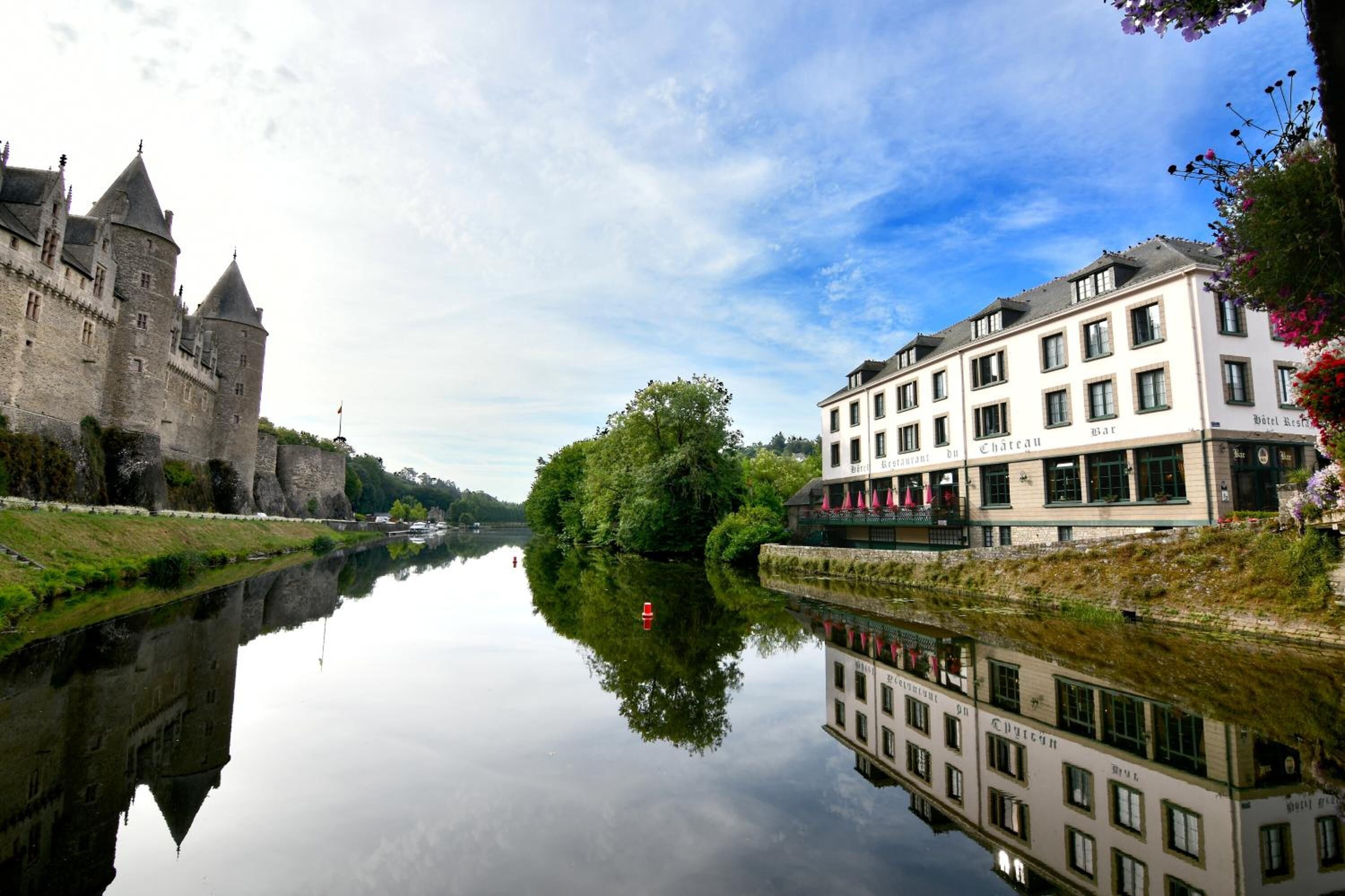 Un castillo y un hotel junto a un río tranquilo.