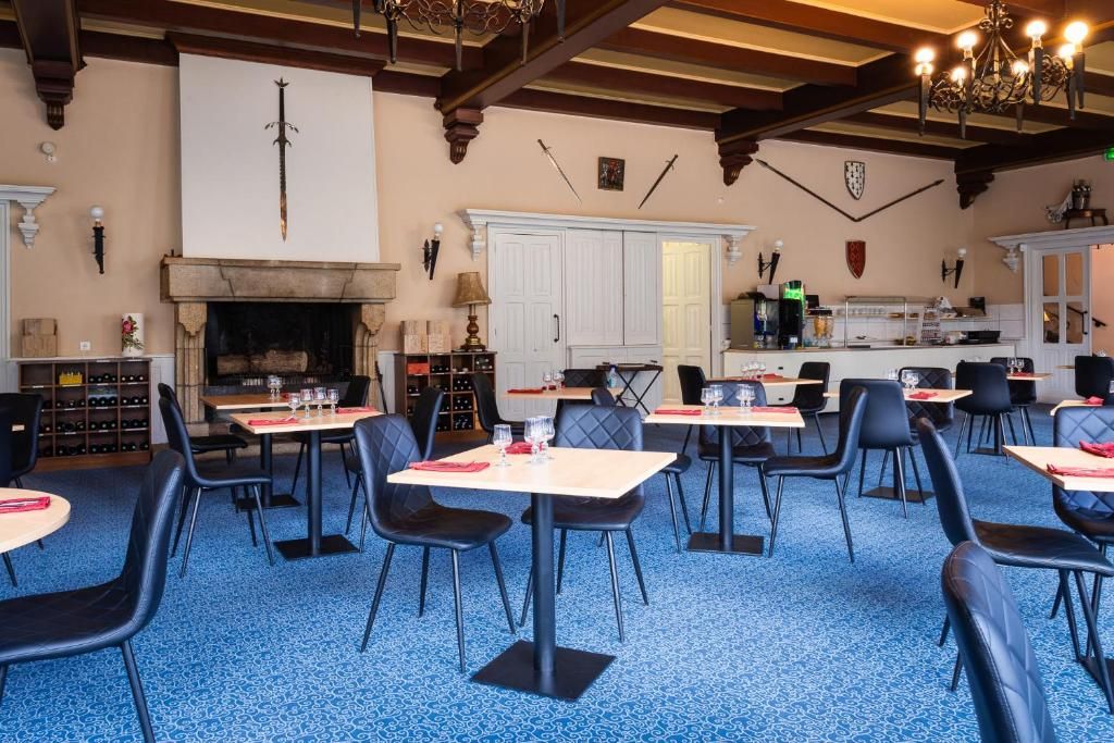 A dining area with tables and chairs, a fireplace, and a kitchen in the background.