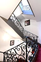 Uma escadaria com elegantes corrimãos de metal preto e um claraboia.