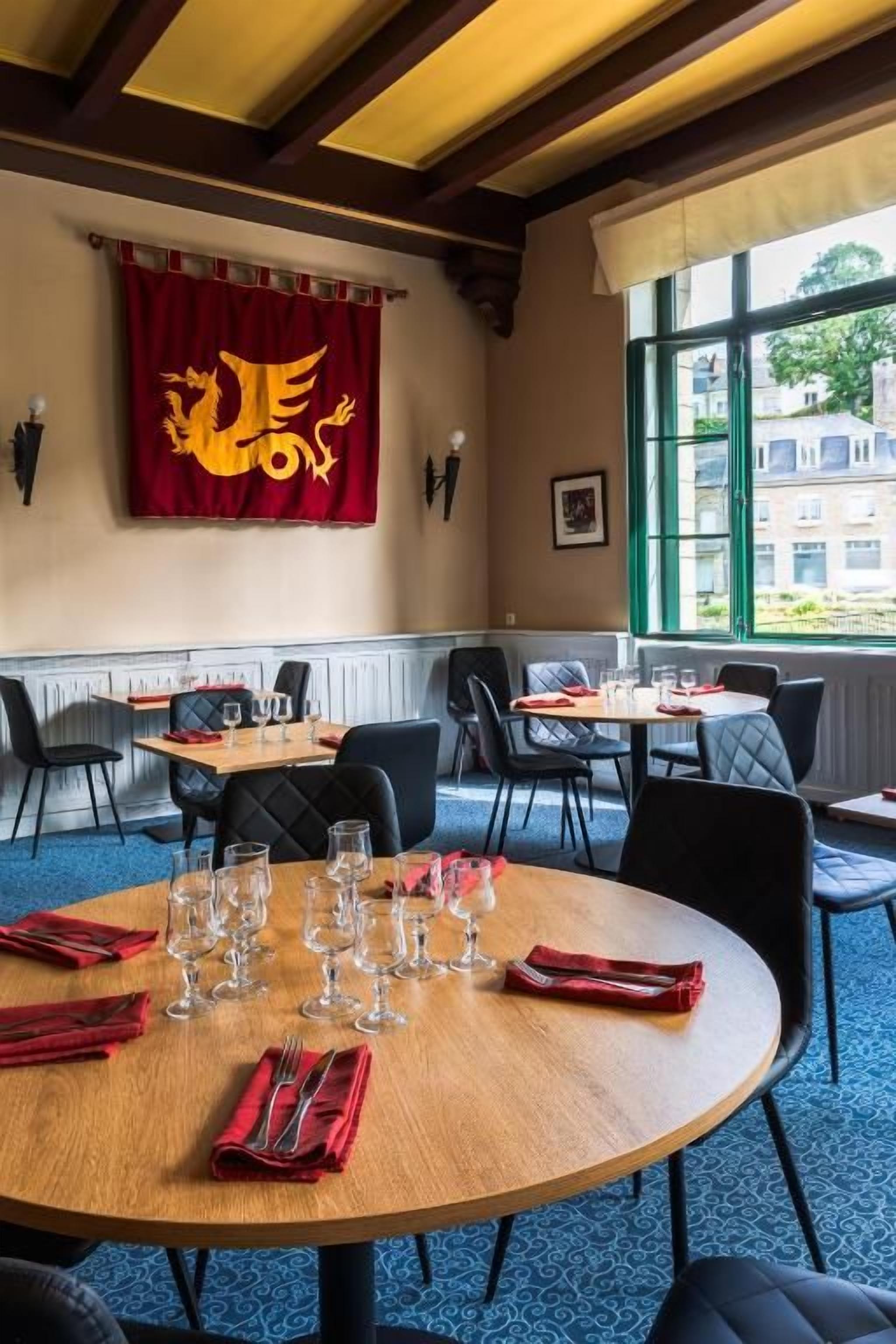 A dining area with round tables, chairs, and a red banner with a golden emblem.