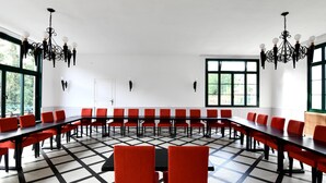 A conference room with long tables and red chairs, large windows, and black chandeliers. - Logis Hotel du Chateau (Josselin)